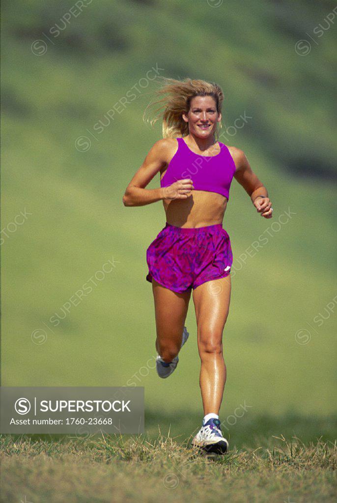 Front View Blonde Woman Running On Grass Green Blurry Bkgd D