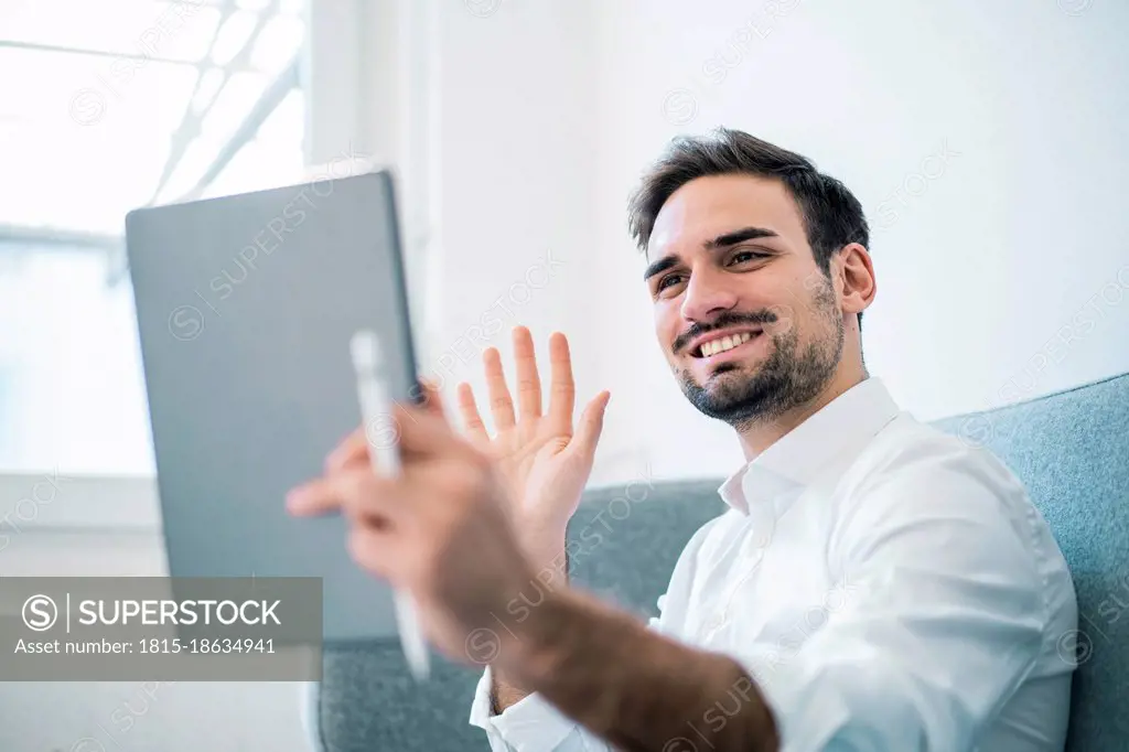 Smiling Male Professional Waving Hand While Doing Video Call Through