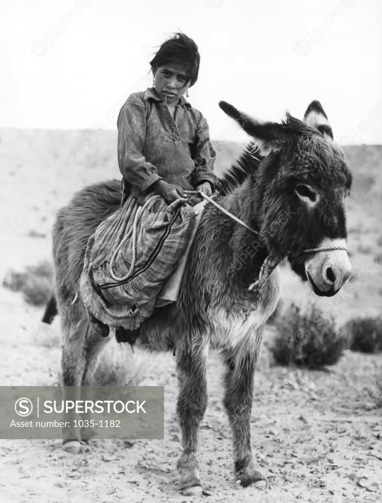 Navajo girl riding a donkey