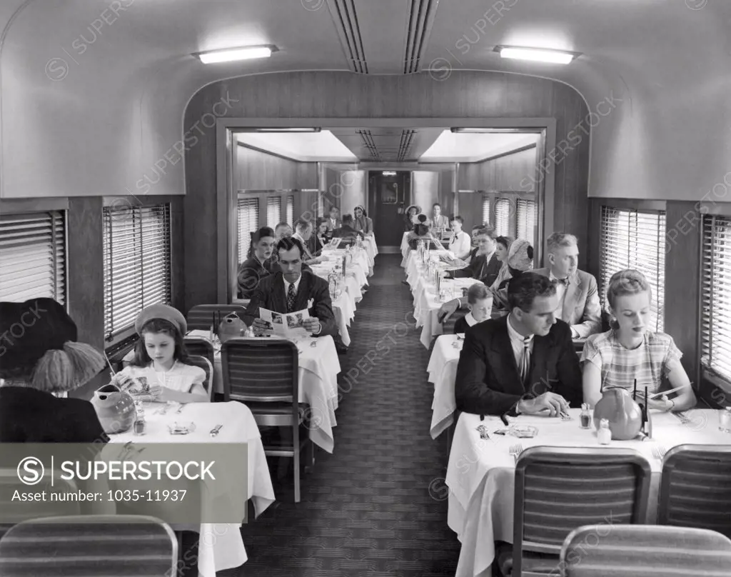 United States:  c. 1940. Passengers on a train in the dining car for dinner.