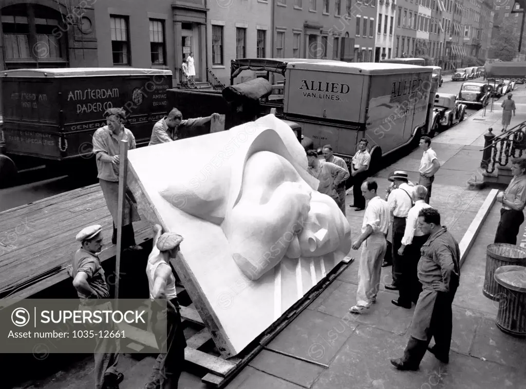 New York, New York:  1940 Isamu Noguchi looking at part of the Associated Press Building Plaque, which was carved in plaster and cast in stainless steel - at that time the largest-ever stainless steel casting.  It is still installed in Rockefeller Center.