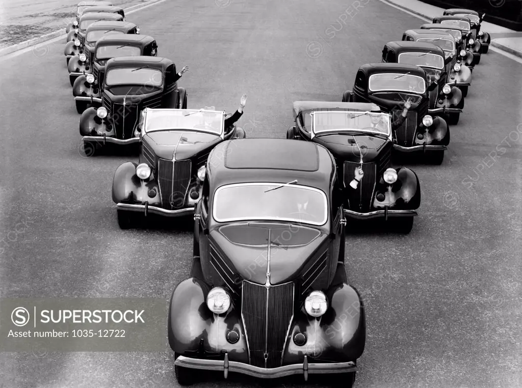 United States: c. 1934 A fleet of fifteen Cadillacs driving down the street in a 'V' formation.