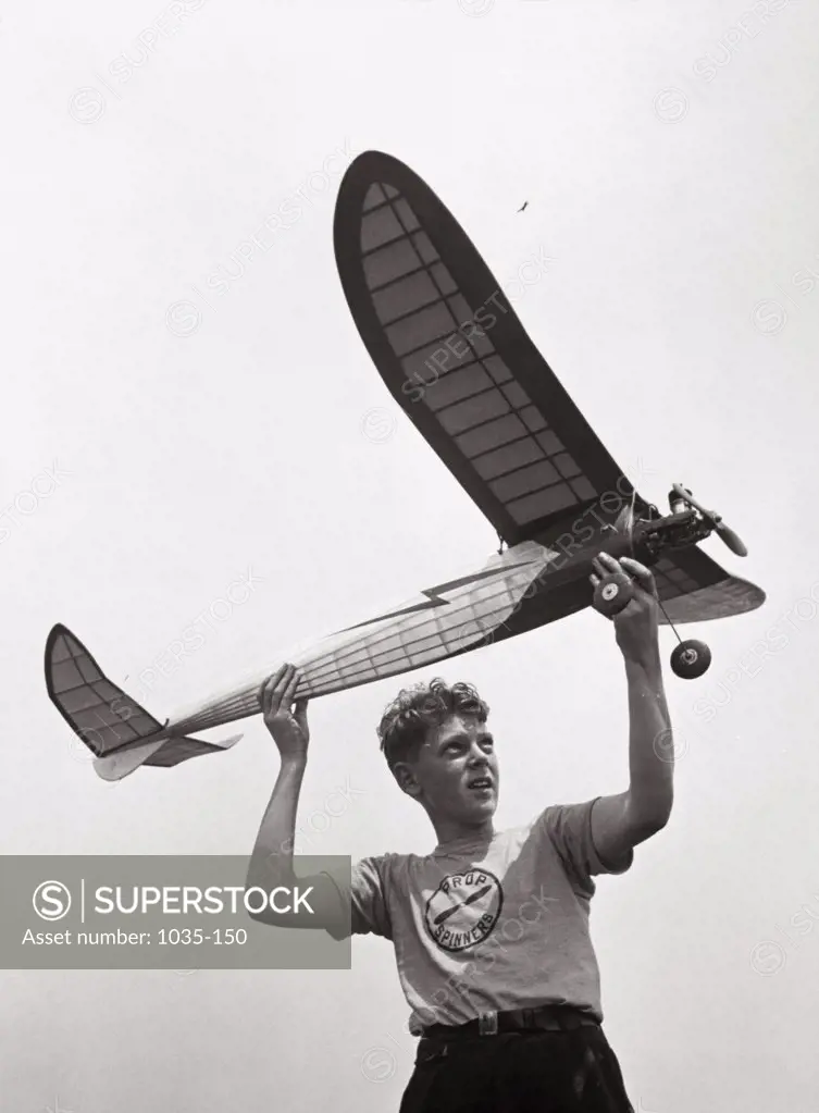 Low angle view of a teenage boy holding a airplane