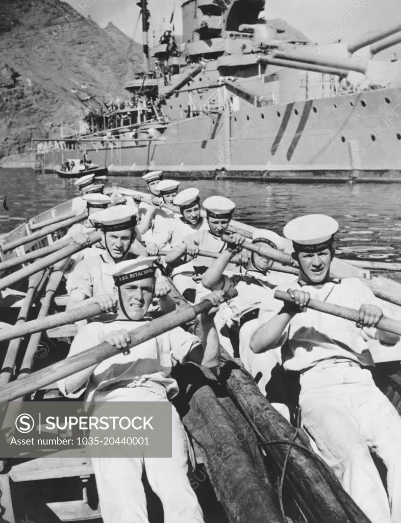 Mediterranean Sea:  February 25, 1937 Seamen of the British Navy lay on the oars as they go through a drill in a cutter of the H.M.S. Royal Sovereign seen in the background.