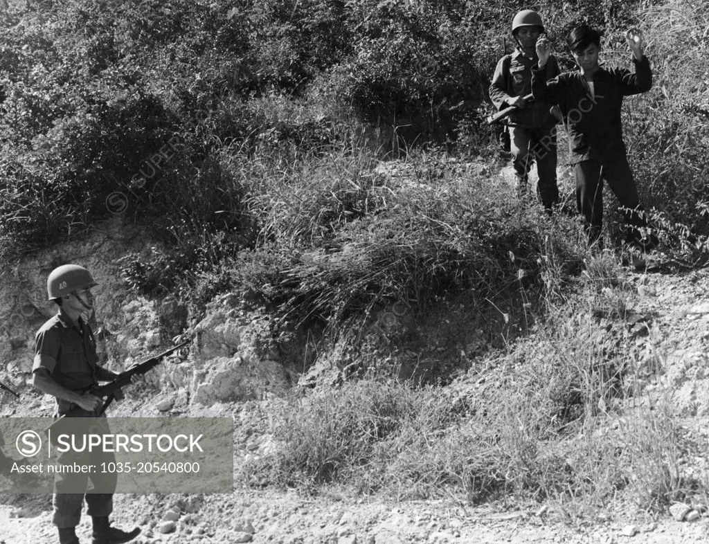 Nha Trang, Vietnam:  February 16, 1966 A Viet Cong guerrilla surrenders to Republic of Vietnam soldiers after seeing psychological warfare leaflets dropped by U.S. Air Force commandos.