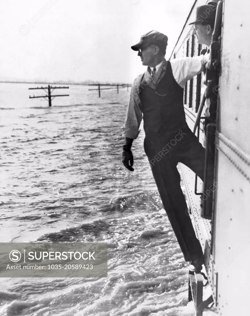 Harrisburg, Illinois:  January 27, 1937 The engineer looks out over a 10 mile pond of Ohio River flood waters as his train on the railway right-of-way ploughs on with relief supplies.