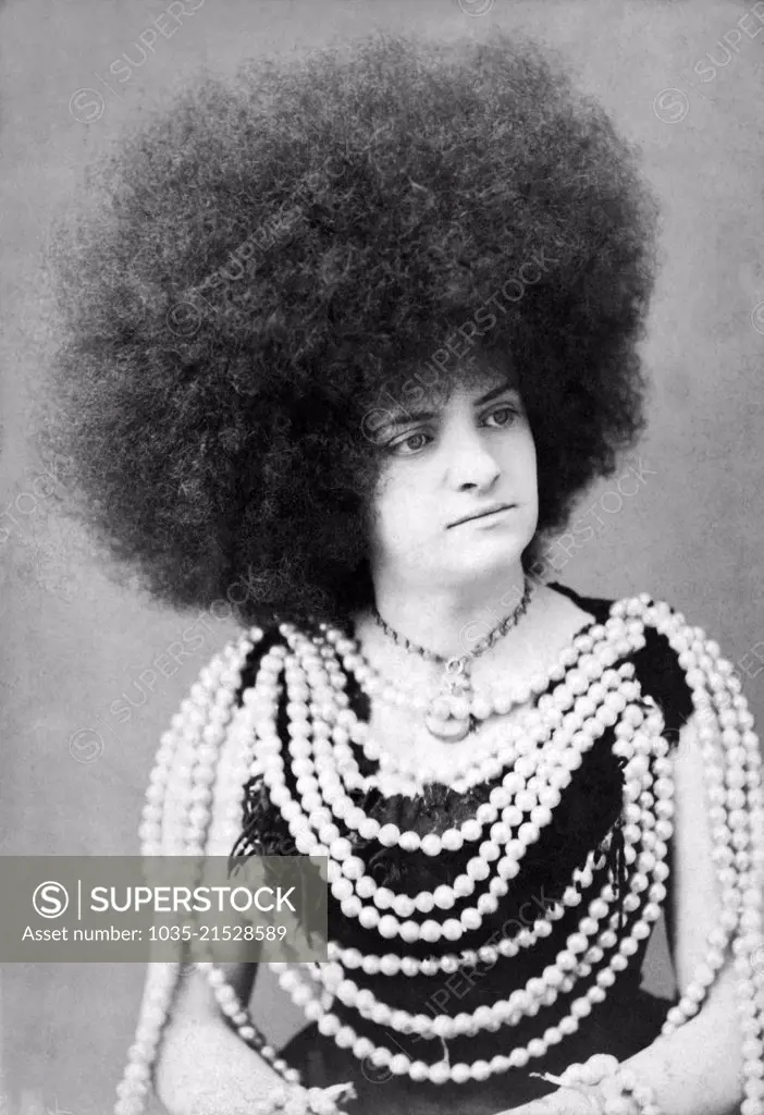 New York, New York:  c. 1880. A protrait of a woman vaudeville or circus performer with an immense afro hairdo and many rows of beads on her body