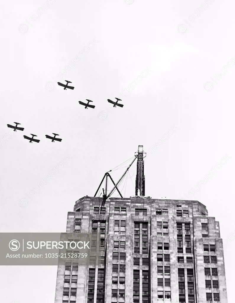 Chicago, Illinois:  July 9, 1930 Six U.S. Army planes fly in formation over the Palmolive building in salute to the Lindbergh Beacon under construction on the top of the building. It will soon be dedicated as the largest and most powerful beacon in the world, having 2 billion candle power and able to  throw a light for 500 miles.