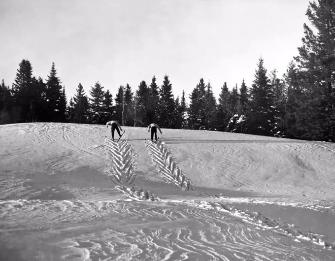 Morin Heights, Quebec, Canada: c. 1959. Two cross country skiers herring-bone up a slope in the Laurentian mountains north of Montreal.