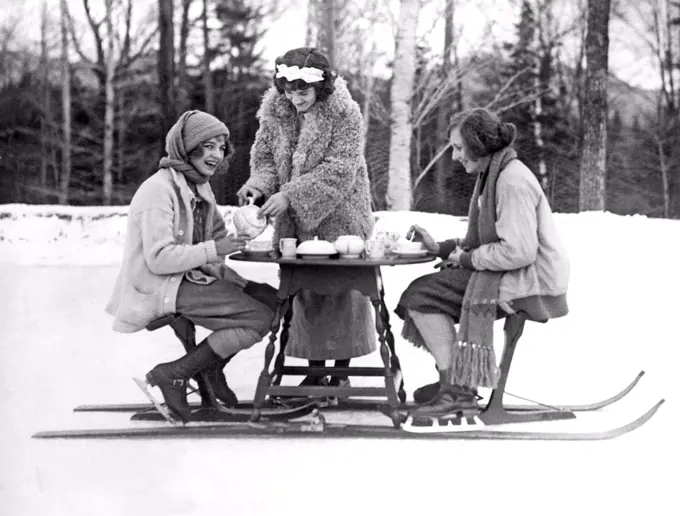 Lake Placid, New York:  January 3, 1923. Two young women ice skaters at the Lake Placid Club enjoy an afternoon tea served hot off the ski-tea table.