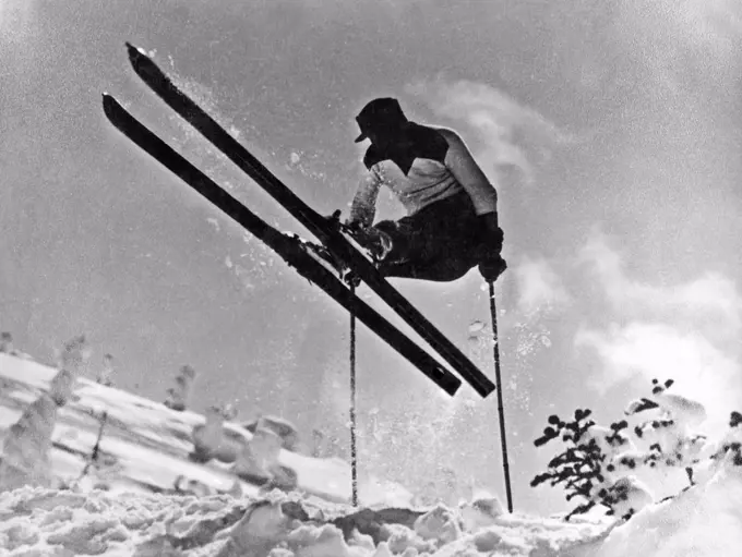 United States:  c. 1933. A skier in profile executes a gelandesprung on the slopes