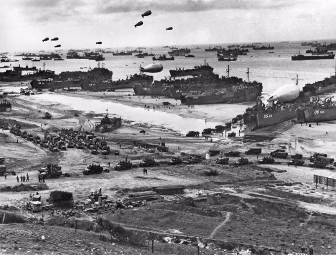 Normandy, France:    July 11, 1944. An endless stream of supplies flow from the transports and landing craft at Normandy, headed for the front in France, while barrage balloons protect the craft from low flying enemy planes.