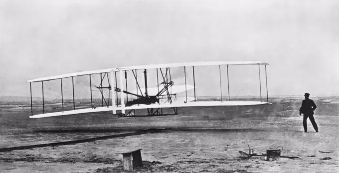 Kitty Hawk, North Carolina:  December 17, 1903 Orville Wright flying during the first powered and sustained flight while Wilbur is on the ground at right.