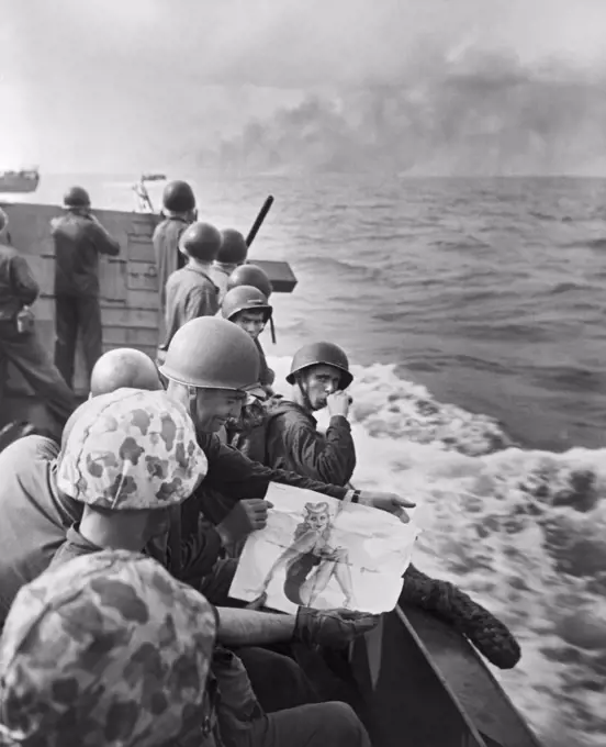 Gilbert Islands, Pacific Ocean:  1943 United States Marines on a landing barge share viewing a pin-up girl as they approach the Japanese held island of Tarawa.