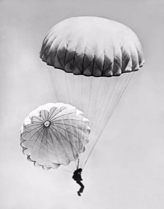 San Diego, California:  August 3, 1927 A Navy "daredevil" from the Coronado Naval Air Station jumps from an airplane using two parachutes, both of which are open.