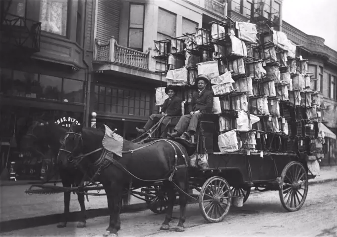 United States:  c.  1900 Two men with a wagon piled high with new chairs.