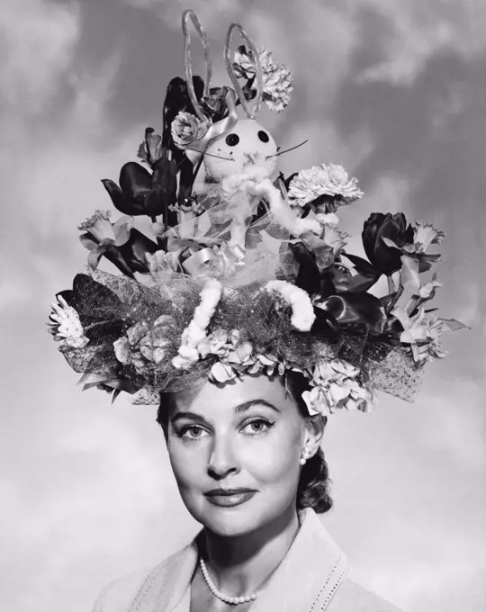 United States:  c. 1950 A portrait of an elegant woman wearing a large Easter bonnet.