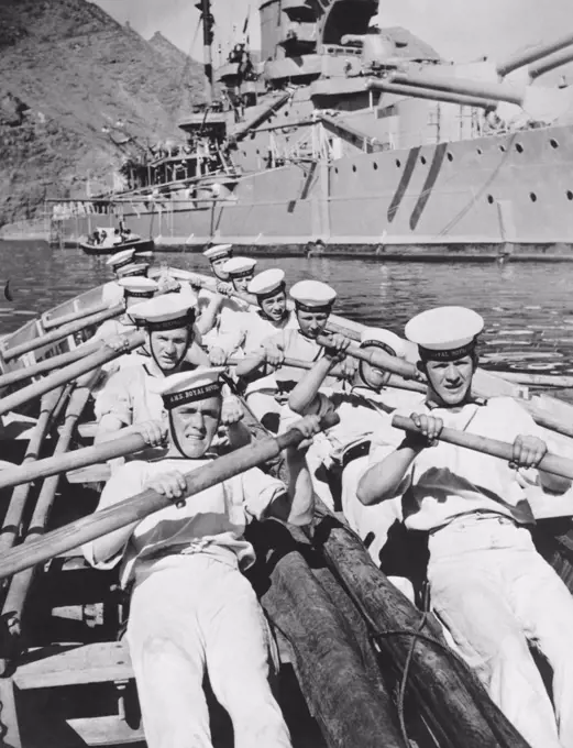 Mediterranean Sea:  February 25, 1937 Seamen of the British Navy lay on the oars as they go through a drill in a cutter of the H.M.S. Royal Sovereign seen in the background.