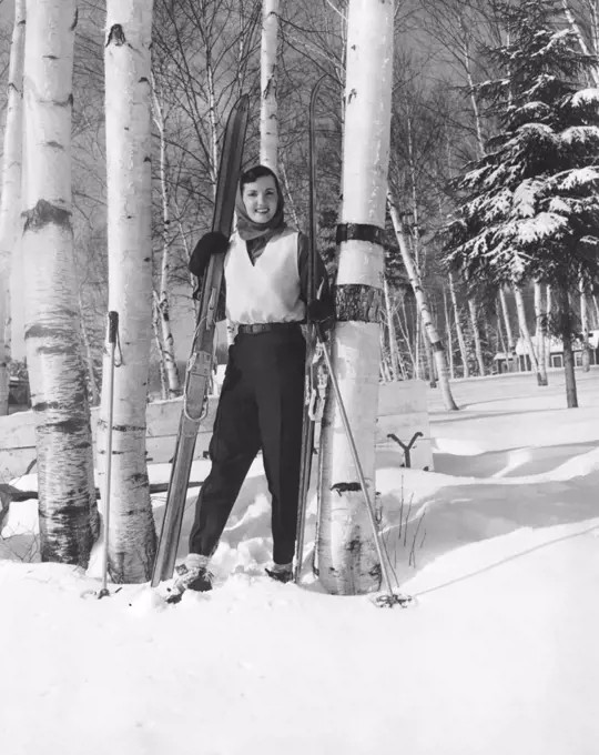 Lake Of Bays, Ontario, Canada:  c. 1956 A young woman with her cross country skis standing in a grove of birch trees.