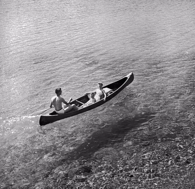 Jasper National Park, Alberta, Canada:  c. 1960 A family paddles a canoe on crystal clear Lac Beauvert on front of the Jasper Park Lodge in the Canadien Rockies.