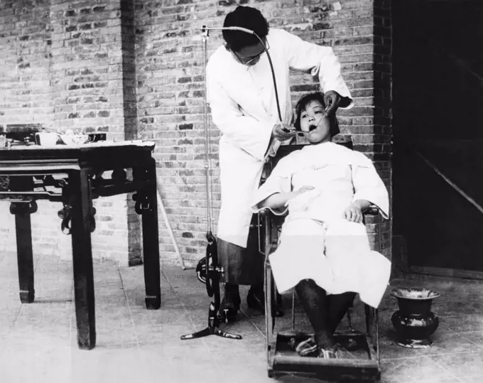 China:  c. 1920 A dentist working on a young girl with a foot powered treadle drill.