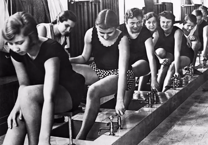 Berlin, Germany:  c. 1929 Pupils at the Dorothea School for gymnastics wash their feet before stepping into the showers after their gym workout.