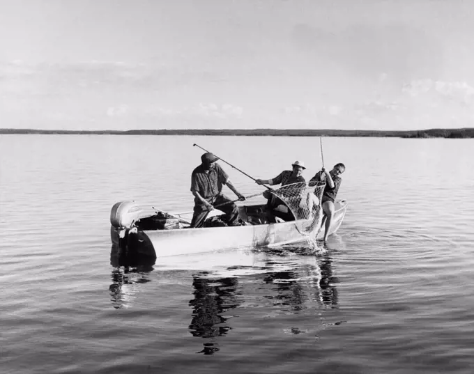 La Ronge, Saskatchewan, Canada:  c. 1960 Fishermen landing a big lake trout on Lac La Ronge in Canada.