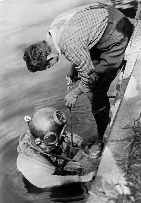 Berlin, Germany:  c. 1932 Photographer and photojopurnalist Willie Ruge and his partner prepare to take the first underwater photographs outside of a diving bell. Their shoes weigh 36 pounds and the combined gear for this venture below the surface of the Elbe River  weighed in at 320 pounds. Here they are getting the final instructions as they descend into the Elbe River.