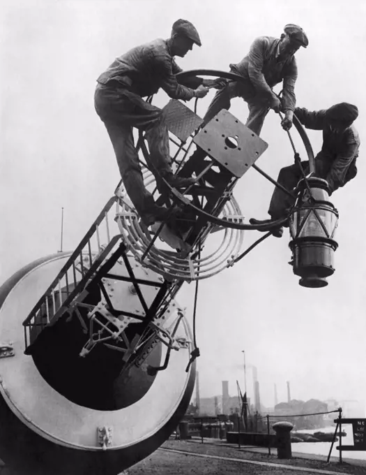 England:  October 13, 1923 Workmen fitting one of the new 900 candle power petroleum vapor lamps to a coastal buoy. They are twice as bright as the old paraffin lamps.