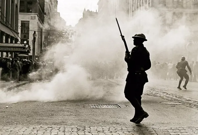 Tacoma, Washington:  1935 A National Guardsman with his fixed bayonet is silhouetted against clouds of tear gas during the months long lumber and mill workers strike.