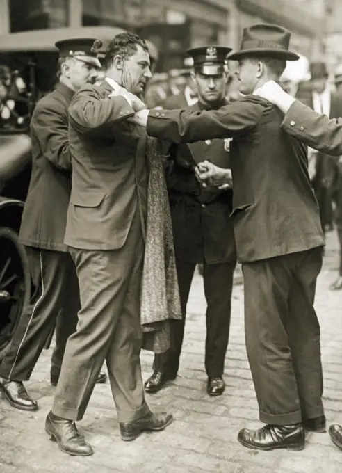 New York, New York:   1916 Policemen and a detective arrest a bloodied trolley car striker during riots in the Bronx.