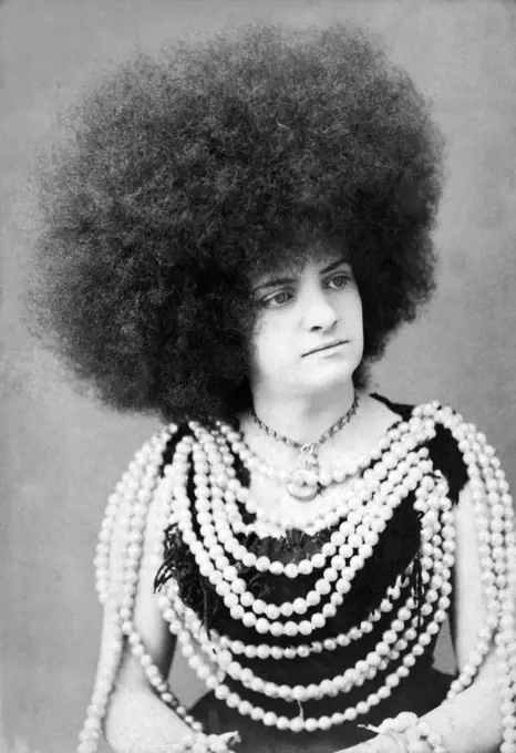 New York, New York:  c. 1880. A protrait of a woman vaudeville or circus performer with an immense afro hairdo and many rows of beads on her body