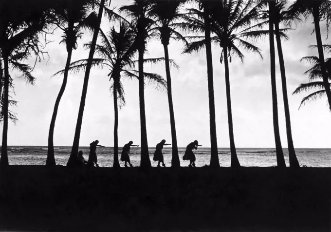 Hawaii:  c. 1922 Folk dancing in Hawaii. Natives at sunsset doing the hula-hula dance under the palms by the water's edge.