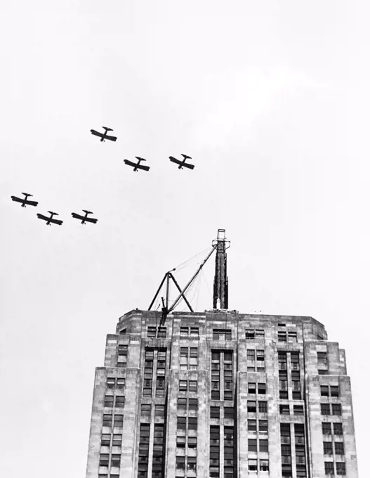 Chicago, Illinois:  July 9, 1930 Six U.S. Army planes fly in formation over the Palmolive building in salute to the Lindbergh Beacon under construction on the top of the building. It will soon be dedicated as the largest and most powerful beacon in the world, having 2 billion candle power and able to  throw a light for 500 miles.