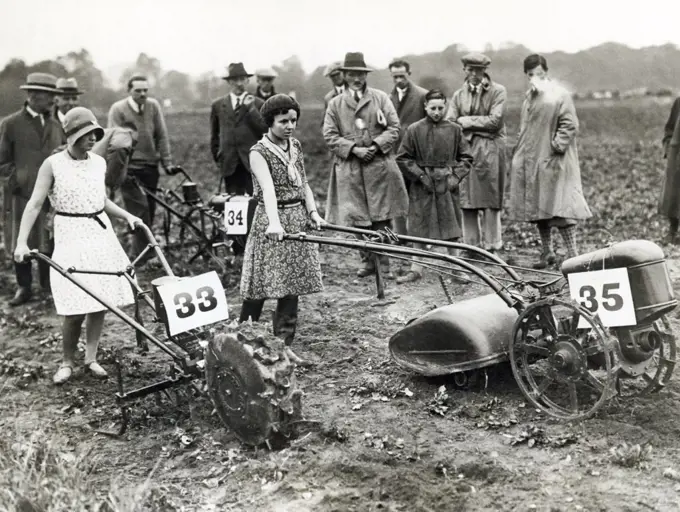 Berlin, Germany:  c. 1928 Two young girls demonstrate the ease with which these new gasoline powered hand tractors for the small farm be may be operated.