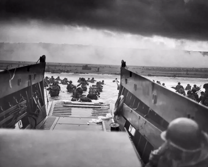 Normandy, France:   June 6, 1944  A Landing Craft Vehicle, Personnel, (LCVP), the USS Samuel Chase, disembarks troops of Company E, 16th Infantry, 1st Infantry Division (the Big Red One) onto the Fox Green section of Omaha Beach on the morning of D-Day. The American soldiers encountered withering machine gun fire from the German 352nd Division while wading ashore. During the initial landing, two-thirds of Company E became casualties. Photo by Robert Sargent, U.S. Coast Guard.