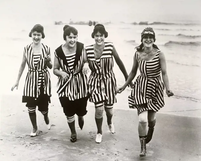 Portrait of four young women running on the beach