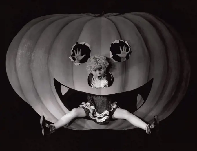 Portrait of a girl sitting in a cut out of a carved pumpkin