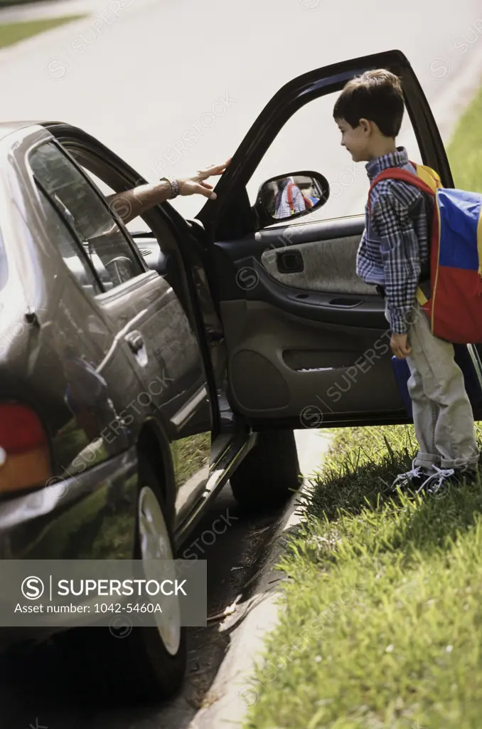 Boy standing in front of the open door of a car