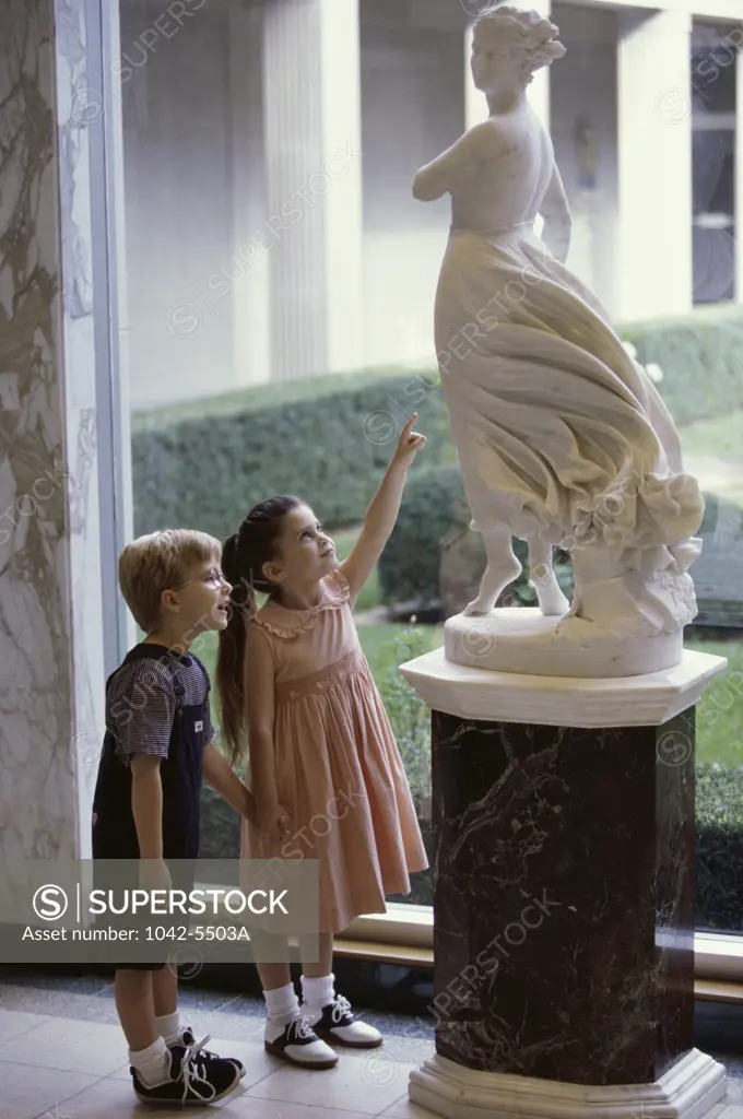 Side profile of a boy and a girl looking at a statue