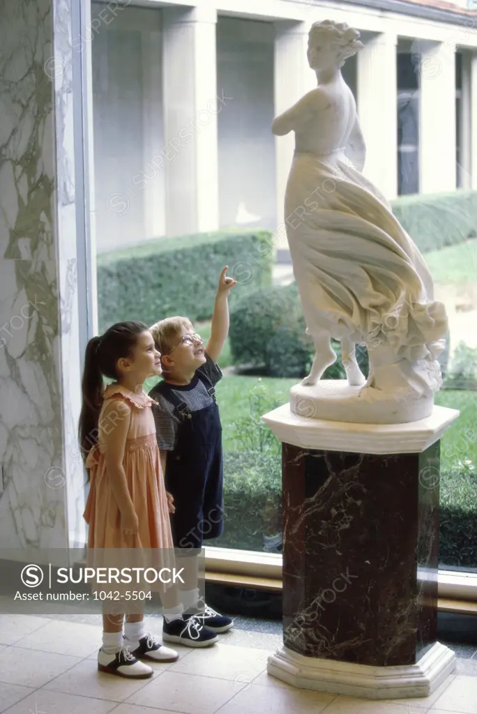 Side profile of a boy and a girl looking at a statue