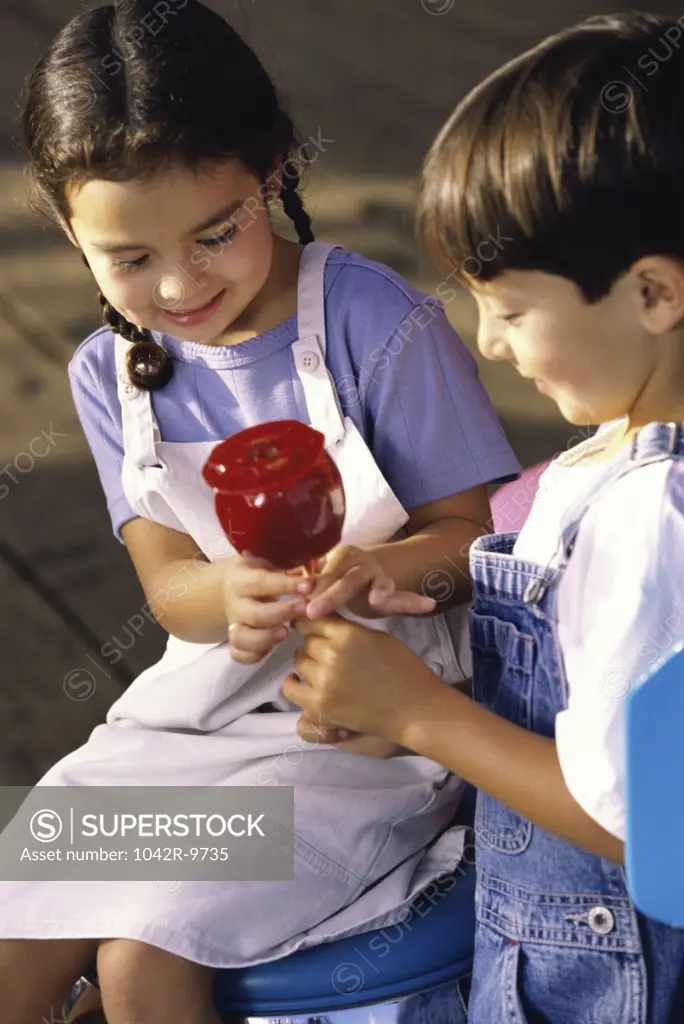 Girl and a boy sitting together holding a candy apple