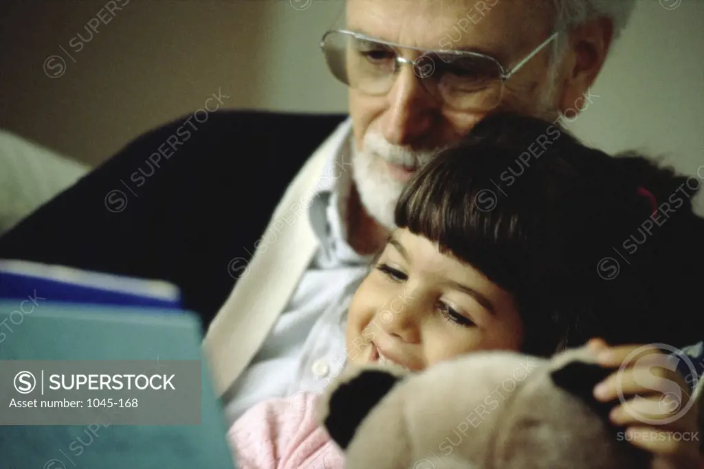 Grandfather reading a book with his granddaughter