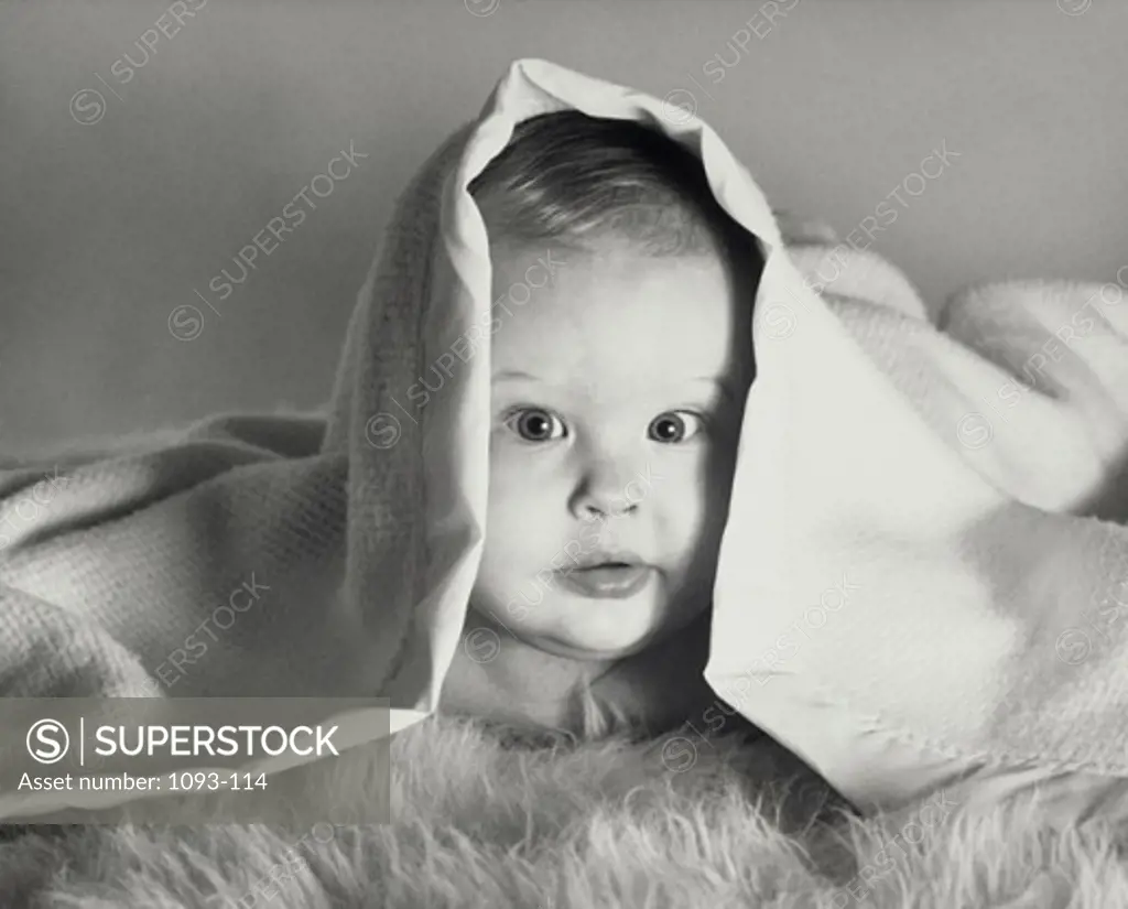 Portrait of a baby boy peeking from a blanket