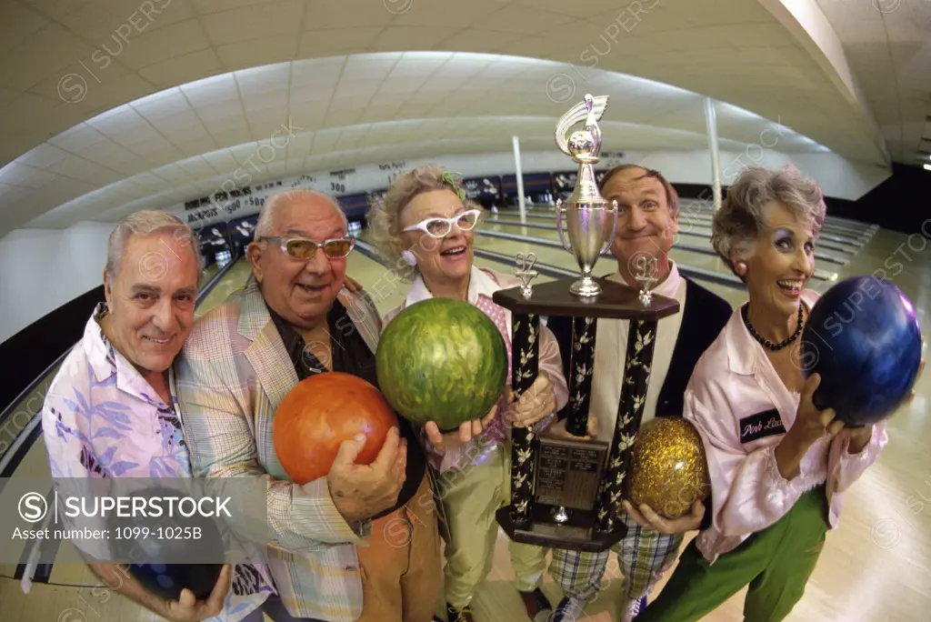 Portrait of a group of senior people holding a bowling trophy at a bowling alley