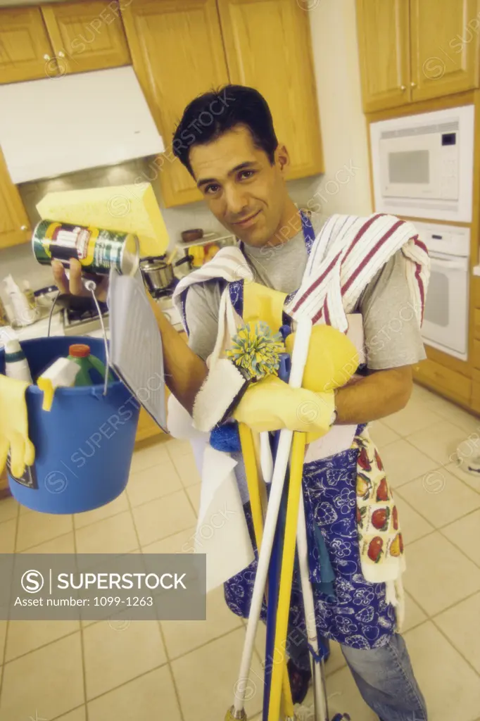 Young man holding cleaning equipment in the kitchen