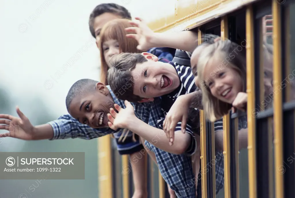 Group of schoolboys and schoolgirls looking out from the window of a school bus