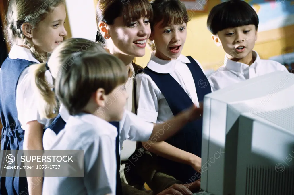 Female teacher with her students in front of a computer