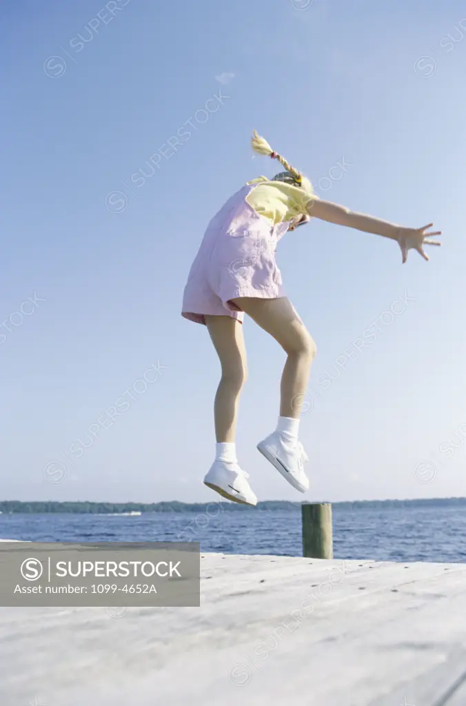 Girl jumping on a dock