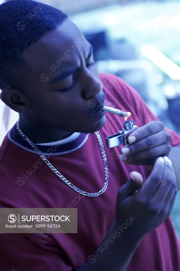 Side profile of a young man lighting a cigarette